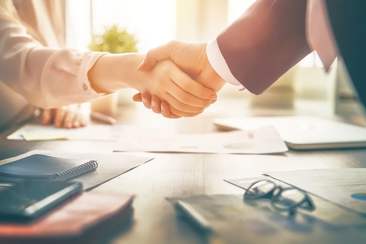 Businessman and businesswoman shaking hands above desk