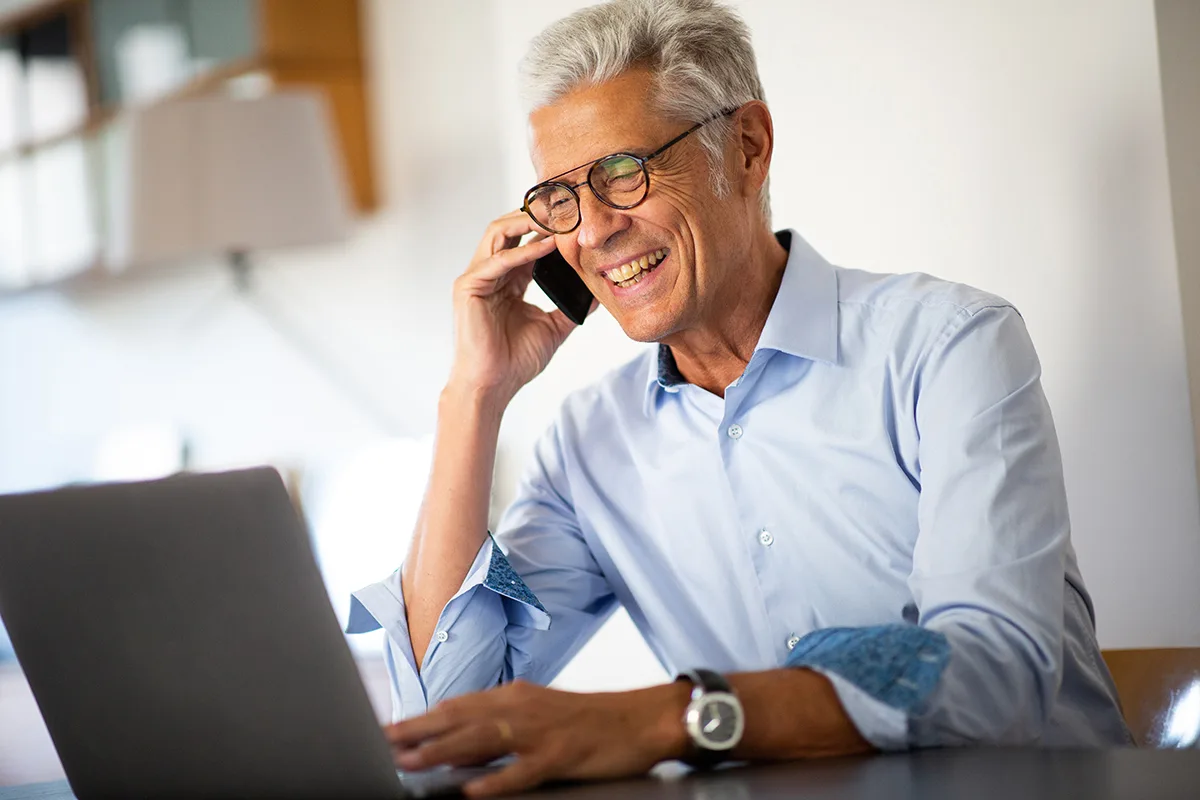 Close up smiling businessman talking with phone while looking at