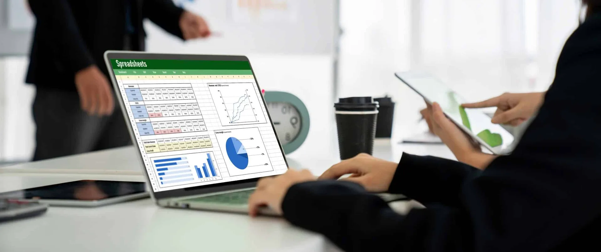 Person reviewing financial spreadsheet on laptop with printed documents on desk