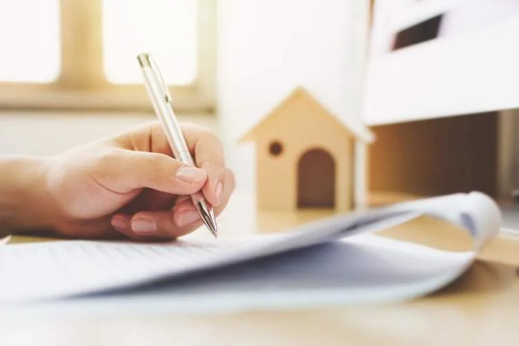 close-up-hand-of-man-signing-signature-loan-document-to-home-and-picture-id947072134