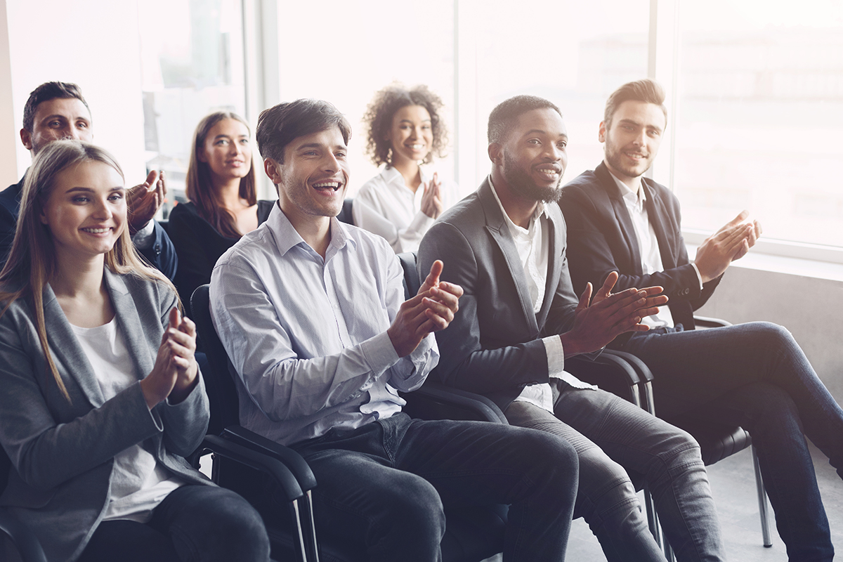 Happy business people clapping hands at conference