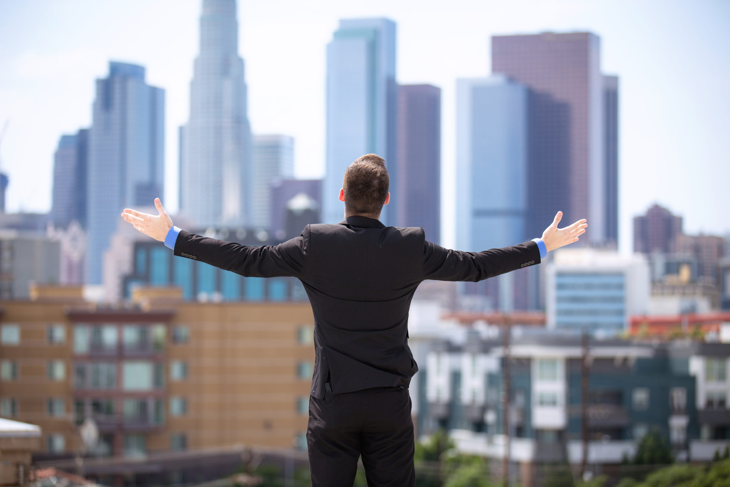 Glory happy businessman arms raised to the sky downtown skyline buildings